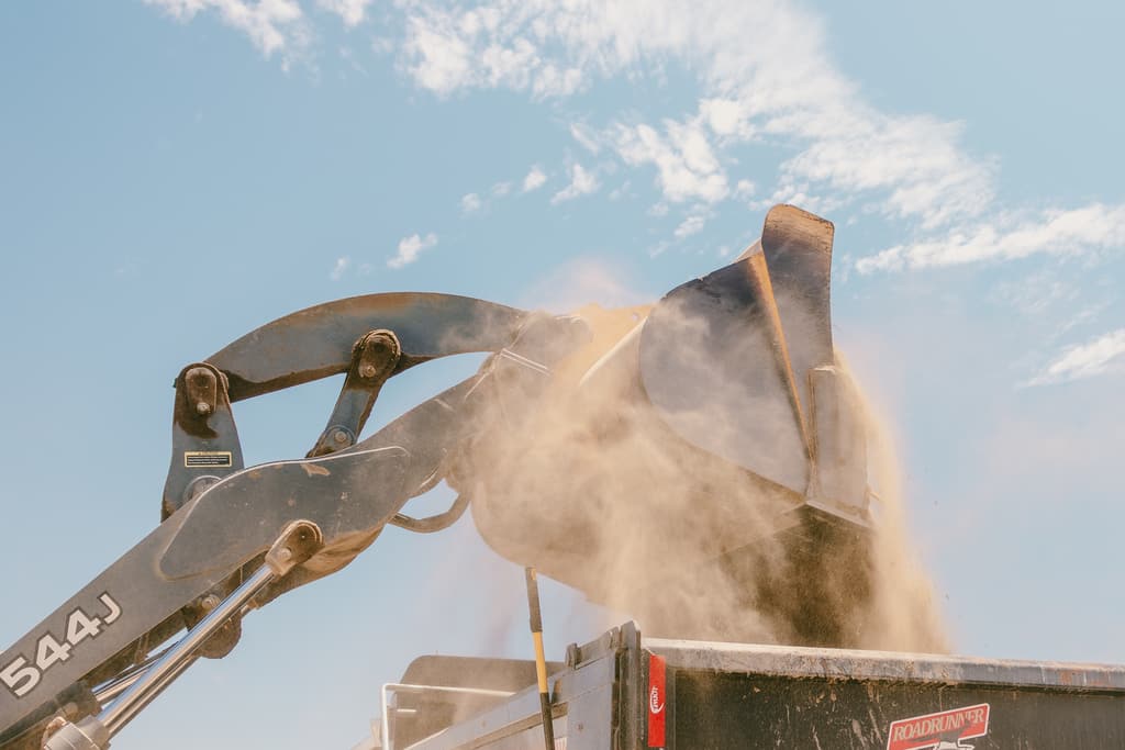 Wheel loader tipping a bucket of dirt into a dump truck bed